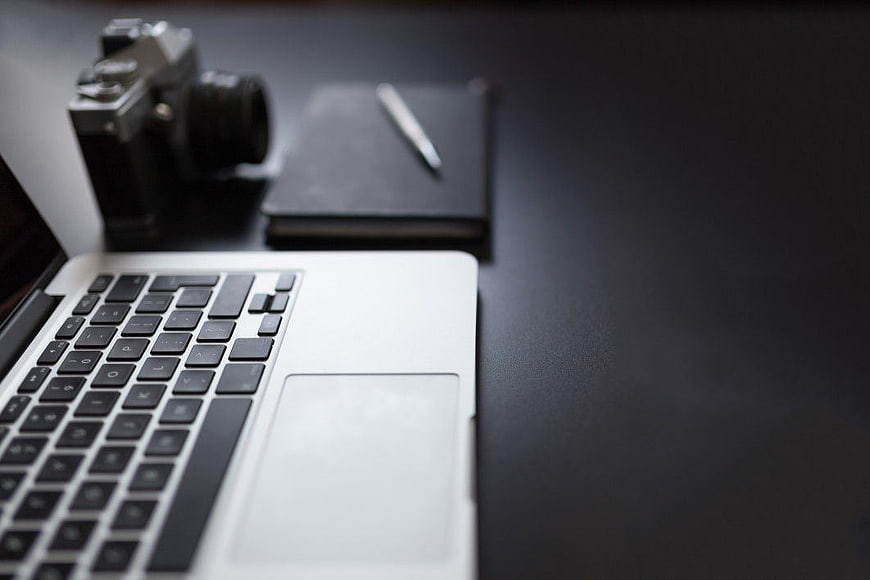 Minimalist workspace with laptop, vintage camera, and notebook