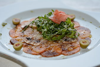 Gourmet Carpaccio with Arugula and Olives on White Plate