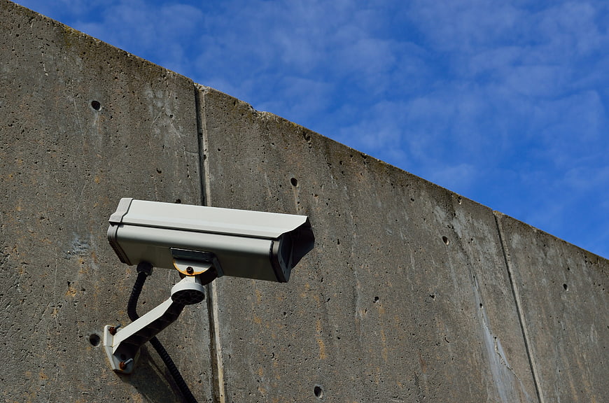 Security Camera Mounted on Concrete Wall Against Blue Sky