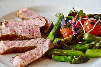 Sliced Veal Steak With Asparagus And Tomatoes On White Plate