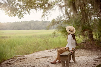 Woman in Straw Hat Sitting on Bench in Nature