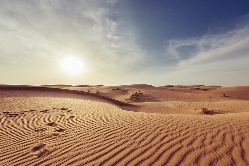 Golden sand dunes with footprints under a bright blue sky