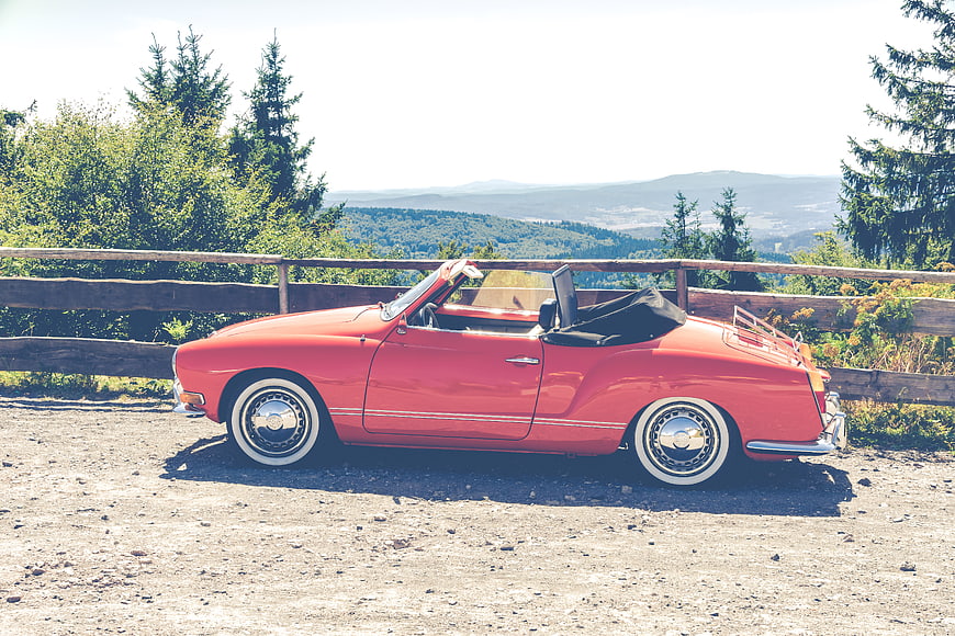 Red vintage convertible parked on scenic mountain overlook