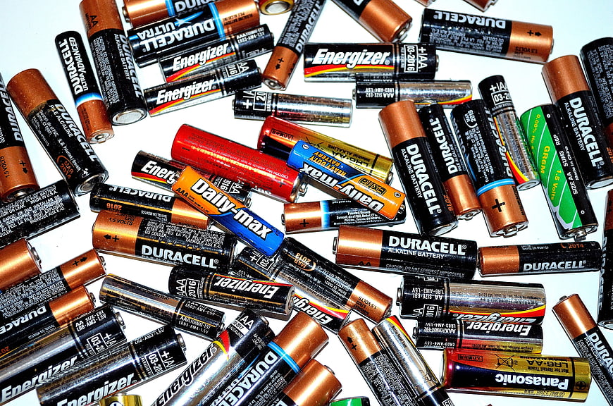 Scattered pile of AA and AAA batteries on white background