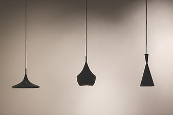 Three modern black pendant lights hanging against a neutral wall