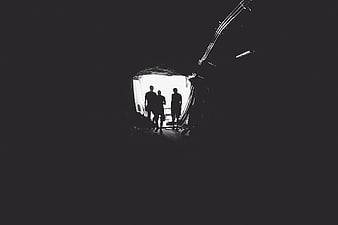 Silhouettes of three people standing in a dark tunnel entrance