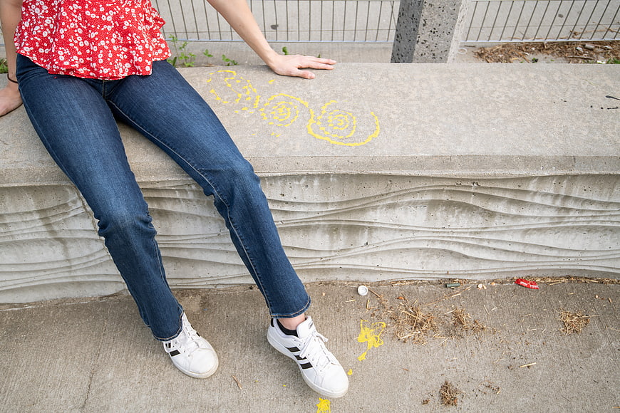 Woman in Jeans and Sneakers Sitting on Concrete Bench