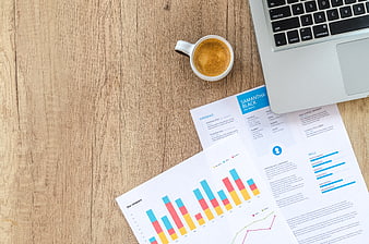 Flat lay of business documents, laptop, and coffee on wooden desk