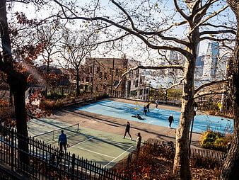 People Playing Pickleball in Urban Park with City Skyline