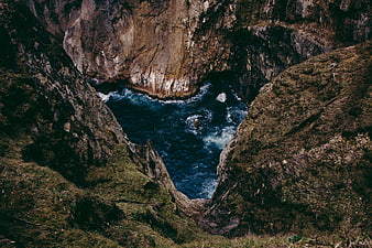 Dramatic coastal cave with crashing waves and rugged cliffs