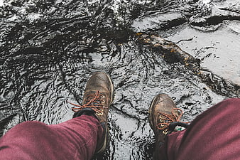 First-person view of hiking boots dangling over rushing river water