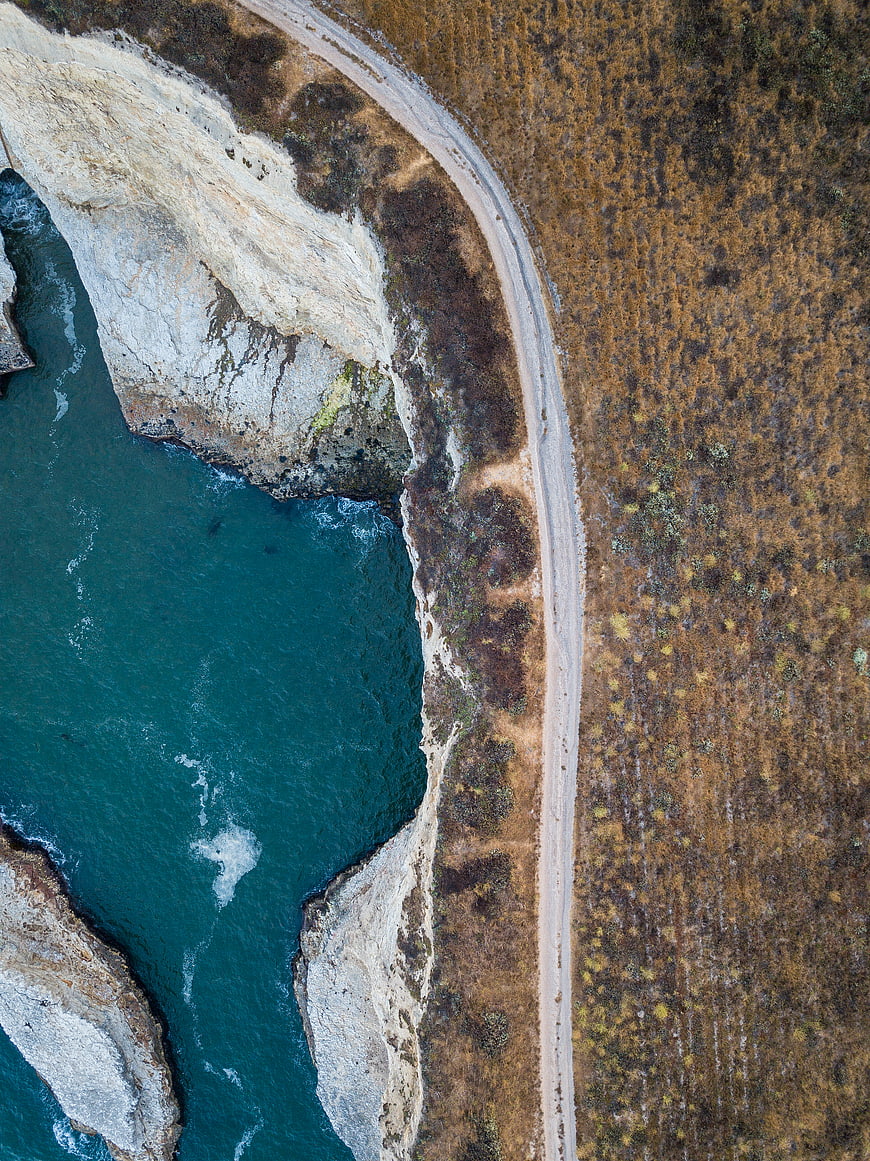 Aerial view of coastal road along rugged cliffs and ocean