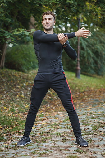 Smiling Man Stretching Arms in Autumn Park