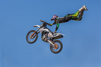 Extreme Motorcycle Freestyle Rider Performing Aerial Stunt Against Blue Sky