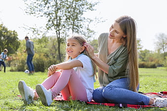 Mother and daughter relaxing on picnic blanket in park