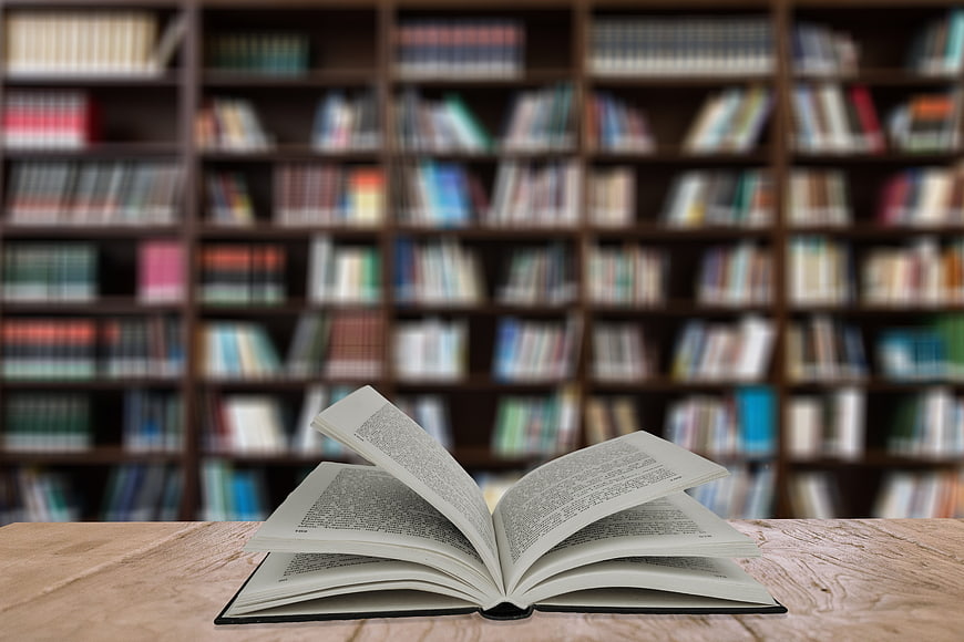 Open Book on Wooden Table with Blurred Library Background