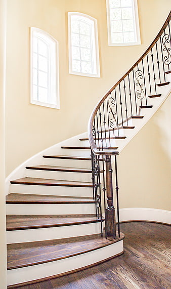 Elegant curved wooden staircase with wrought iron railing in a bright interior