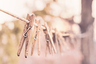 Weathered wooden clothespins hanging on a rope against a soft, blurred background