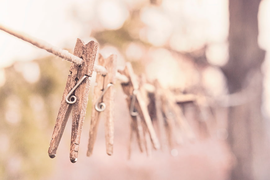 Weathered wooden clothespins hanging on a rope against a soft, blurred background