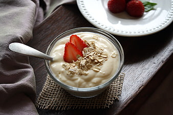 Healthy yogurt bowl with strawberries and oats on wooden table