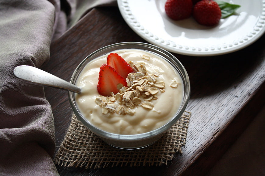 Healthy yogurt bowl with strawberries and oats on wooden table