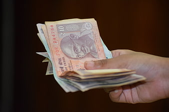 Hand Holding Indian Rupee Banknotes Against Dark Background