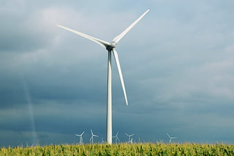 Wind Turbine In Green Field Under Dramatic Cloudy Sky