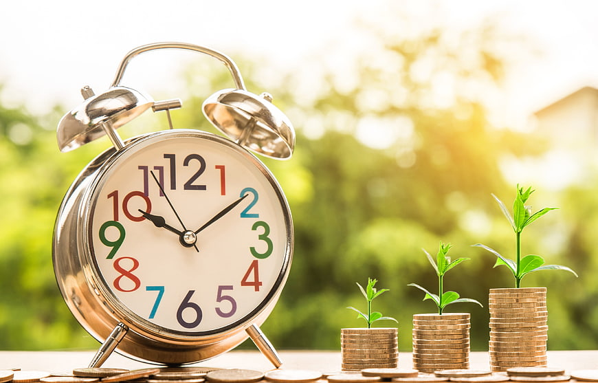 Alarm clock and growing coin stacks with plants