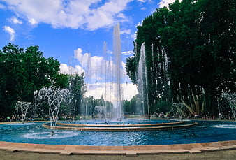 Grand fountain in Budapest park with blue sky and trees