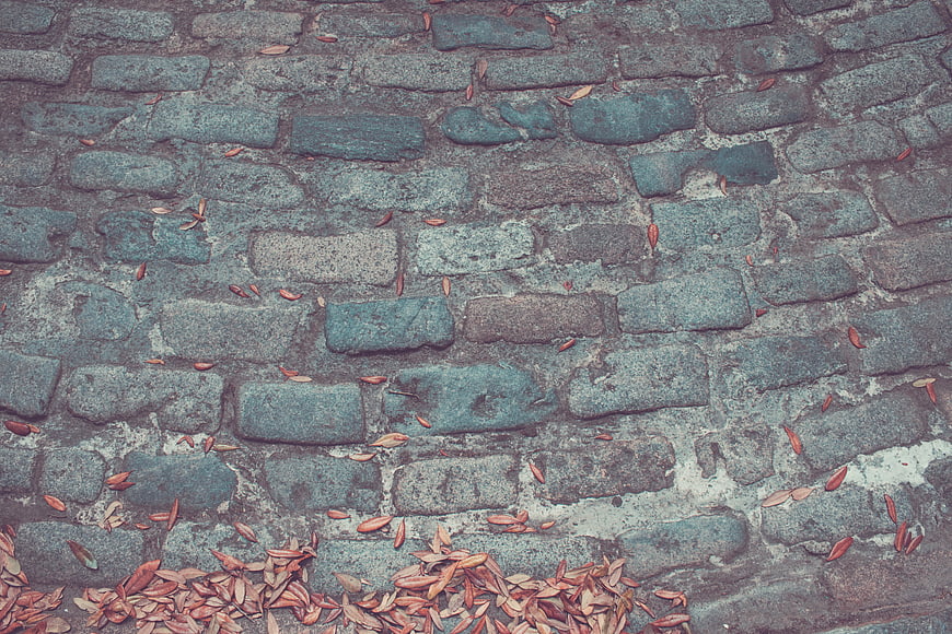 Textured Cobblestone Wall with Scattered Autumn Leaves