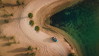 Aerial View of Blue Car on Sandy Shore by Green Water