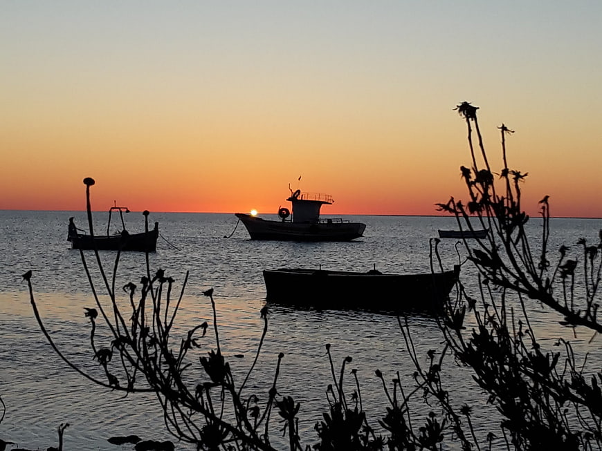 Silhouetted Fishing Boats Anchored at Sunset Over Calm Sea
