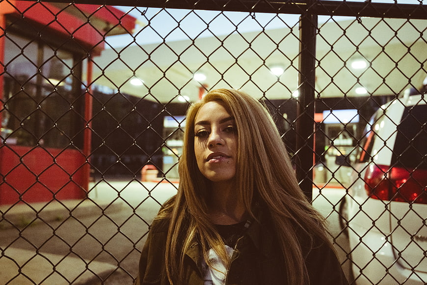 Young woman portrait behind chain link fence at night