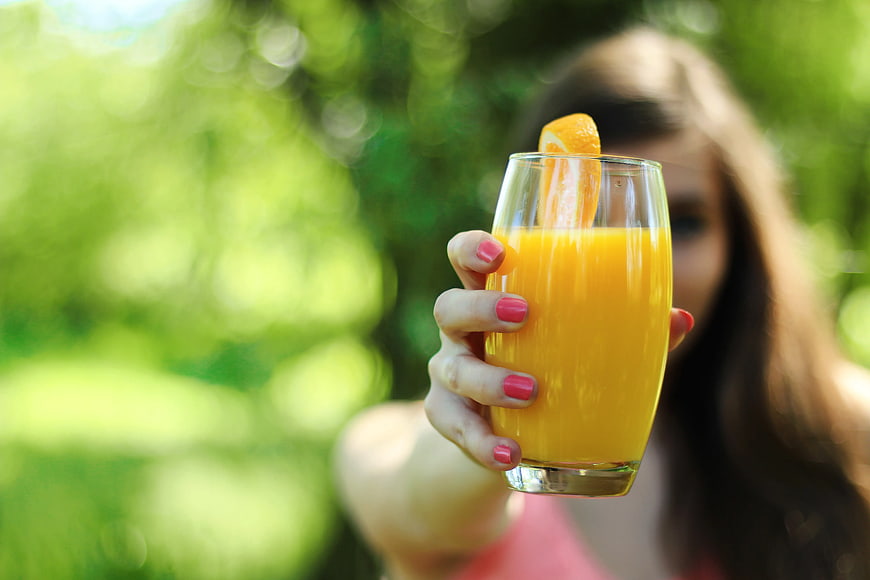 Woman Holding Fresh Orange Juice in Glass Outdoors