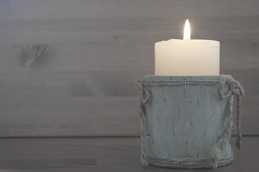 Rustic Lit Candle in Wooden Holder on Gray Background