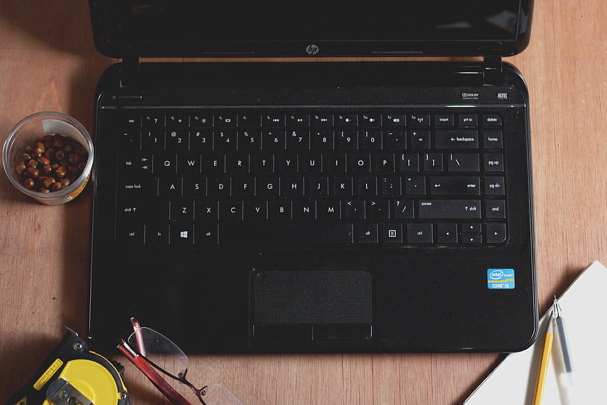 Top-down view of black laptop workspace with coffee beans and tools