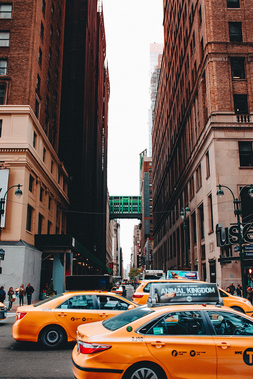 Yellow taxis on a busy New York City street with tall buildings