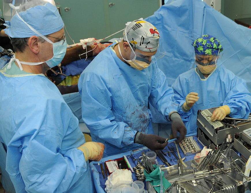Medical team performing surgery with instruments in operating room