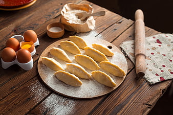 Homemade dumplings on wooden board with eggs and flour
