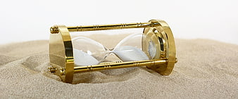 Gold hourglass lying on sand representing time