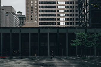 Lone Man Walking in Urban Plaza with Modern Architecture