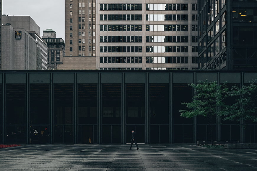 Lone Man Walking in Urban Plaza with Modern Architecture