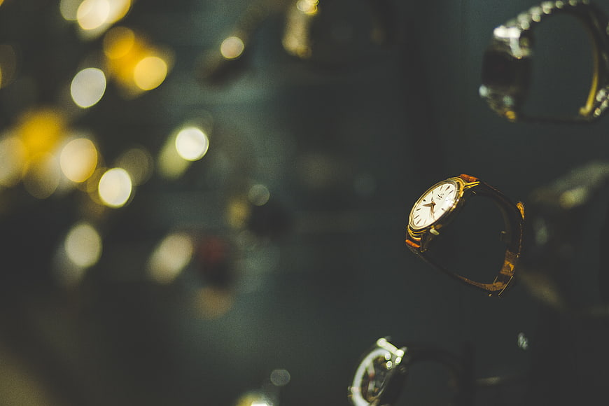 Luxury gold wristwatch in display case with bokeh background