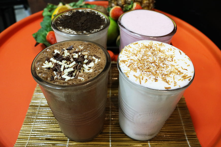 Four Gourmet Smoothies with Toppings on Orange Tray