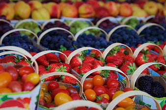 Colorful baskets of fresh berries and tomatoes at a market