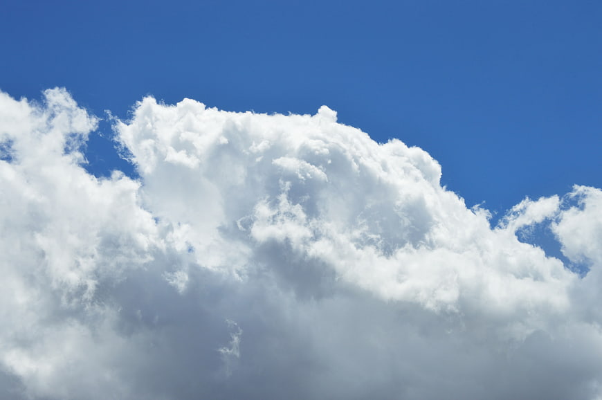 Fluffy white cumulus clouds against a deep blue sky