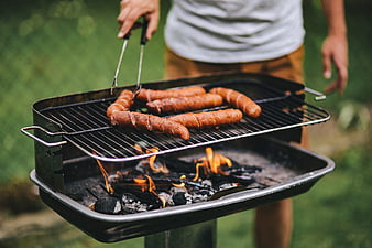 Man grilling sausages on charcoal barbecue outdoors