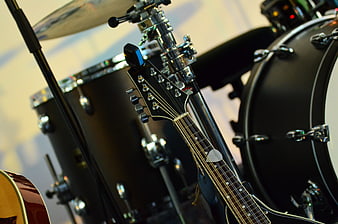 Close-up of electric guitar headstock and black drum kit