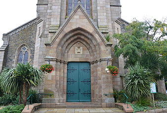 Historic Gothic Church Entrance With Green Wooden Doors And Hanging Flowers