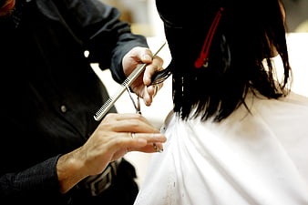 Close-up of hairdresser cutting woman's hair with scissors